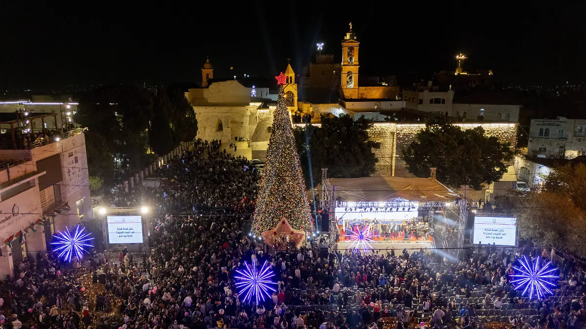 A-large-crowd-gathers-to-watch-a-live-performance-on-stage-during-the-tree-lighting-ceremony-in-Manger-Square-in-Bethlehem-in-the-occupied-West-Bank-on-December-6-2025-Christmas-celebrations-resume-in-the-city-after-a-two-year-hiatus-caused-by-the-war-Preparations-for-the-holiday-take-place-amid-an-ongoing-ceasefire-between-Israel-and-Hamas