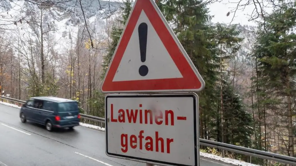 Ein-Schild-mit-der-Aufschrift-Lawinengefahr-steht-an-einer-Strasse