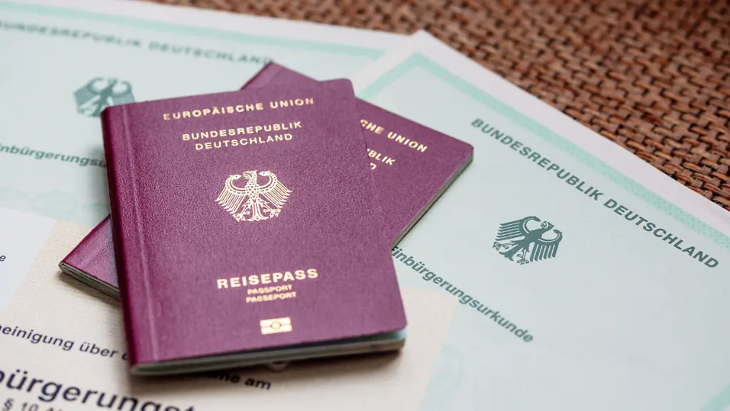 Zwei-deutsche-Reisepaesse-liegen-auf-Einbuergerungsurkunden-der-Bundesrepublik-Deutschland-sowie-einem-Einbuergerungstest