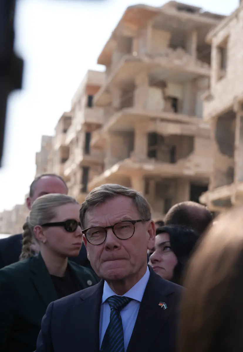 Johann-Wadephul-M-CDU-Bundesminister-des-Auswaertigen-steht-wahrend-seines-Besuchs-eines-humanitaeren-Projekts-in-einer-Strasse-vor-waehrend-des-Buergerkriegs-zerstoerten-Haeusern-Bei-seinem-Besuch-in-Syrien-zeigt-sich-Aussenminister-Wadephul-erschuettert-ueber-ds-Ausmass-der-Zerstoerungen