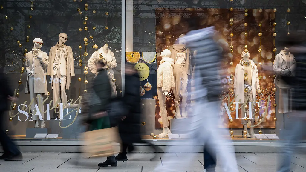 Menschen-eilen-in-der-Einkaufsstrasse-Zeil-an-einem-festlich-geschmueckten-Schaufenster-vorbei-das-mit-SALE-und-winterlicher-Dekoration-fuer-das-Weihnachtsgeschaeft-wirbt-Im-Vorweihnachtsgeschaeft-verbuchen-viele-Einzelhaendler-noch-einmal-ein-Umsatzplus