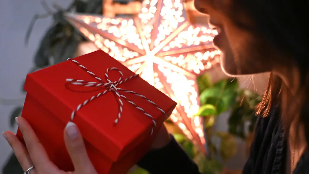 ILLUSTRATION-06-12-2025-Berlin-Eine-Frau-haelt-eine-mit-einer-Schleife-verzierte-Geschenkbox