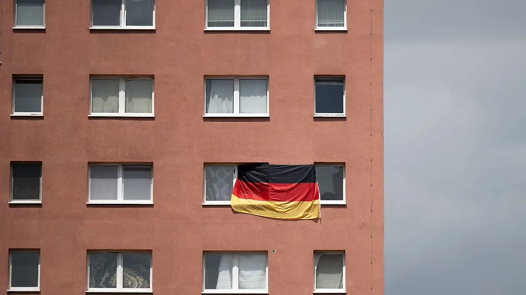 Die-Bundesflagge-haengt-zwischen-zwei-Fenstern-eines-Plattenbaus-in-Halle-Saale
