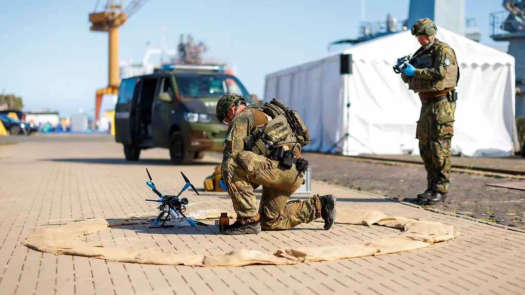 Die-Sicherung-und-der-Schutz-des-strategischen-Seetransports-von-Militaer-Kraeften-nach-Litauen-unter-Nutzung-ziviler-und-militaerischer-verteidigungswichtiger-Infrastruktur-inklusive-der-dafuer-benoetigten-Absicherung-ist-der-Schwerpunkt-der-multinationalen-Militaeruebung-Quadriga-2025-Feldjaeger-der-Bundeswehr-sichern-bei-einem-eine-abgefangene-Flugdrohne-und-sichern-Beweise-Rostock-04-09-2025