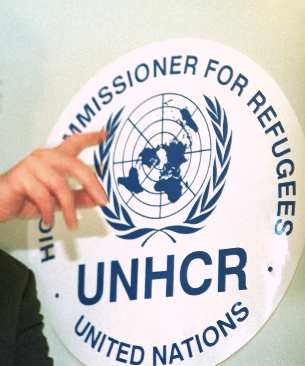 Eine-Hand-weist-am-8-1-2001-im-UNHCR-Hauptquartier-in-Genf-auf-das-das-Logo-der-Hilfsorganisation-Mitarbeiter-von-Hilfsorganisationen-und-UN-Blauhelmsoldaten-haben-angeblich-in-grossem-Umfang-Fluechtlingskinder-in-West-Afrika-sexuell-missbraucht-Zu-diesem-Ergebnis-kommt-ein-am-27-2-2002-veroeffentlichter-Untersuchungsbericht-des-UN-Fluechtlingshilfswerks-UNHCR-und-der-britischen-Hilfsorganisation-Save-the-Children-Kinder-die-fuer-den-Bericht-in-Liberia-Guinea-und-Sierra-Leone-befragt-wurden-beschuldigten-annaehernd-70-Mitarbeiter-von-mehr-als-40-Organisationen-darunter-auch-das-UNHCR-und-Save-the-Children-als-Gegenleistung-fuer-Lebensmittelrationen-Geld-und-Stipendien-Sex-verlangt-zu-haben