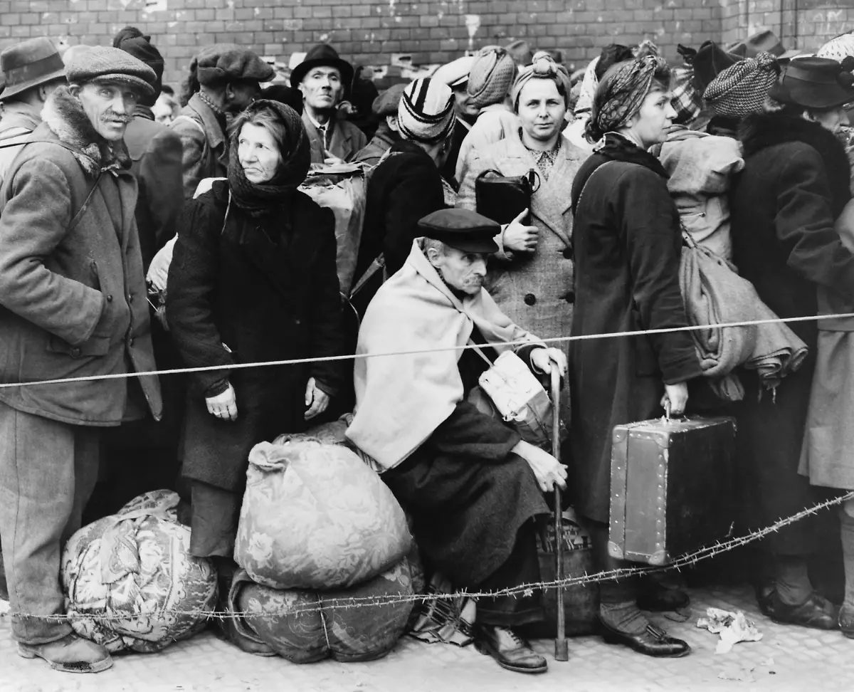 German-displaced-persons-wait-in-Berlin-s-Anhalter-Station-in-1945-Refugees-are-carrying-their-few-belongings-as-the-stand-behind-a-rope-and-double-strand-of-barbed-wire-World-War-2