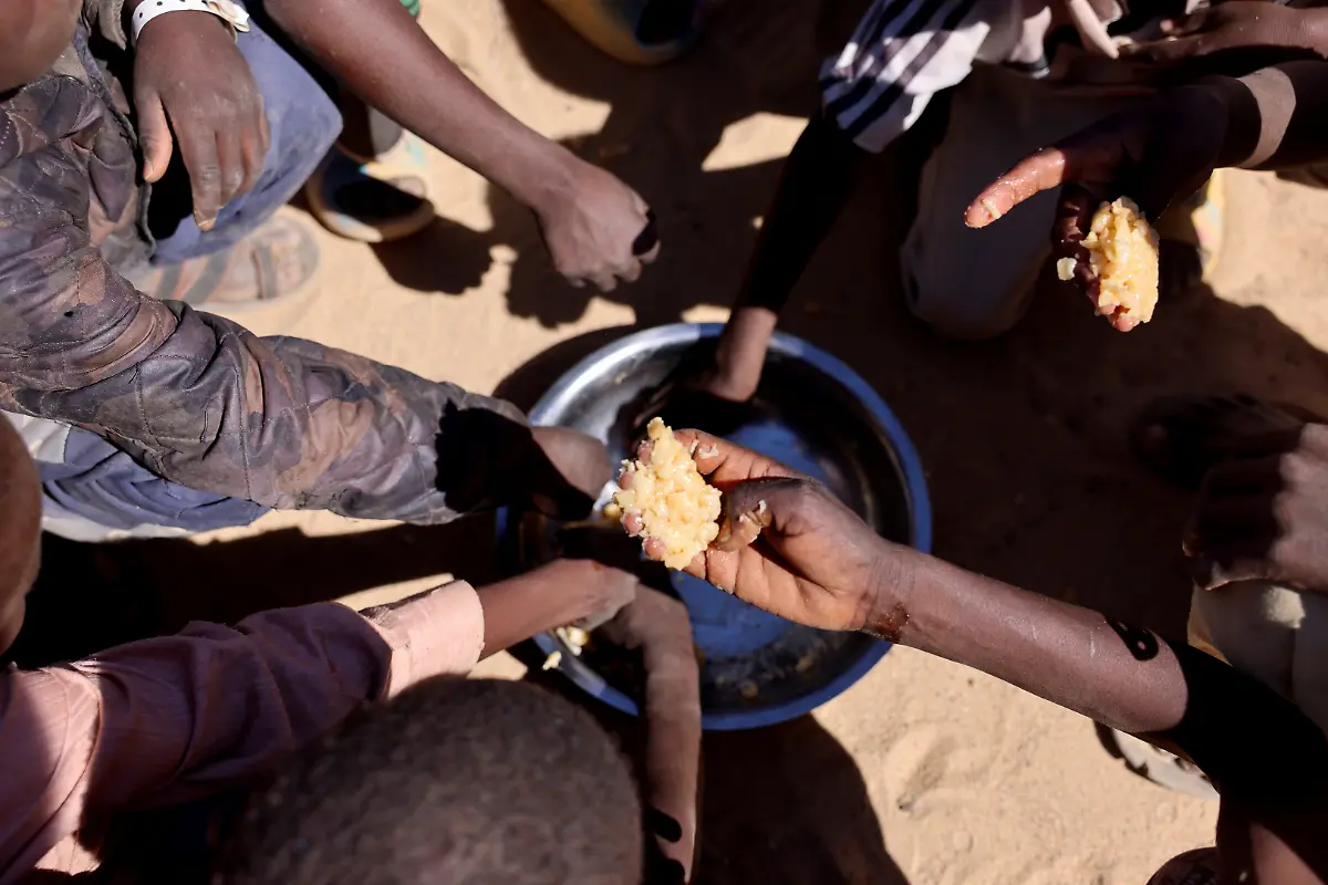 Sudanese-orphaned-refugees-children-from-al-Fashir-share-a-free-meal-of-pasta-and-meat-provided-by-the-Group-Kitchen-Project-led-by-Najwa-Isa-Adam-inside-the-Tine-transit-camp-in-eastern-Chad-as-they-flee-ongoing-clashes-between-the-paramilitary-Rapid-Support-Forces-RSF-and-the-Sudanese-army-November-22-2025