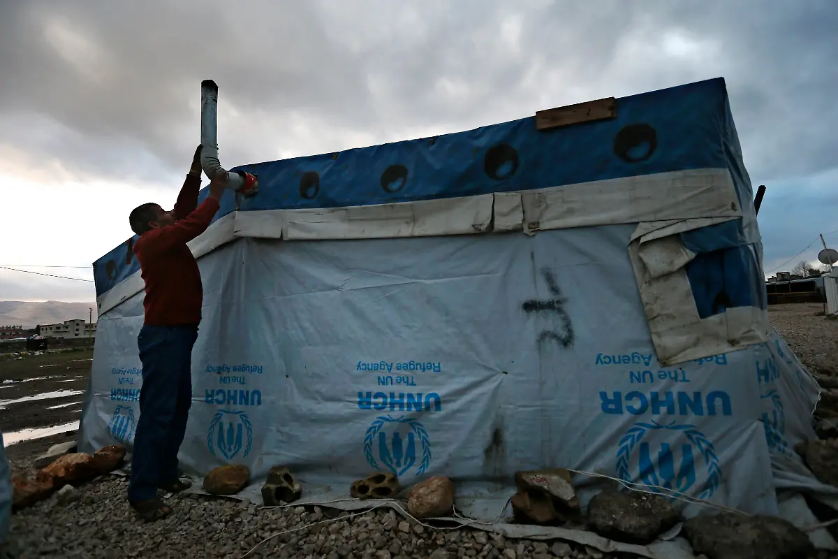 A-Syrian-refugee-fixes-the-stovepipe-of-his-tent-as-he-prepares-for-the-possibility-of-a-snow-storm-at-a-Syrian-refugee-camp-in-Deir-Zannoun-village-Bekaa-valley-Lebanon-Monday-Jan-5-2015-A-snow-storm-is-expected-to-hit-Lebanon-Monday-affecting-Syrian-refugees-many-of-whom-live-in-tents-without-proper-heating-The-government-estimates-there-are-about-1-5-million-Syrians-in-Lebanon-about-one-quarter-of-the-total-population