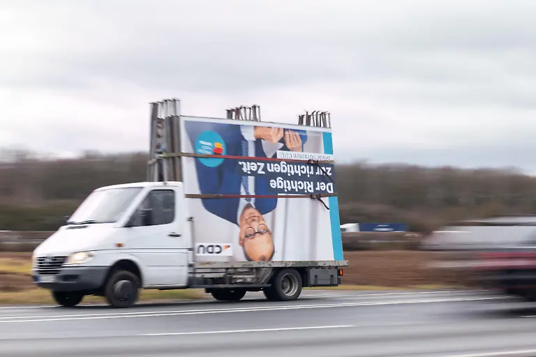 26-02-25-Limburg-Symbolfoto-Illustrationsbild-Symbolbild-Illustrationsfoto-Alltagsszene-Ein-Transporter-faehrt-ueber-eine-Landstrasse-mit-abgebauten-CDU-Wahlplakaten-auf-der-Ladeflaeche-Das-groesste-Plakat-das-mit-Gurten-befestigt-ist-zeigt-Friedrich-Merz-kopfueber-mit-dem-Slogan-Der-Richtige-zur-richtigen-Zeit-Die-Szene-symbolisiert-das-Ende-des-Wahlkampfs-nach-der-Bundestagswahl-2025-bei-der-am-23-Februar-rund-60-Millionen-Bundesbuerger-abgestimmt-haben-Der-Abtransport-der-Wahlwerbung-markiert-den-Abschluss-einer-intensiven-politischen-Auseinandersetzung-im-oeffentlichen-Raum