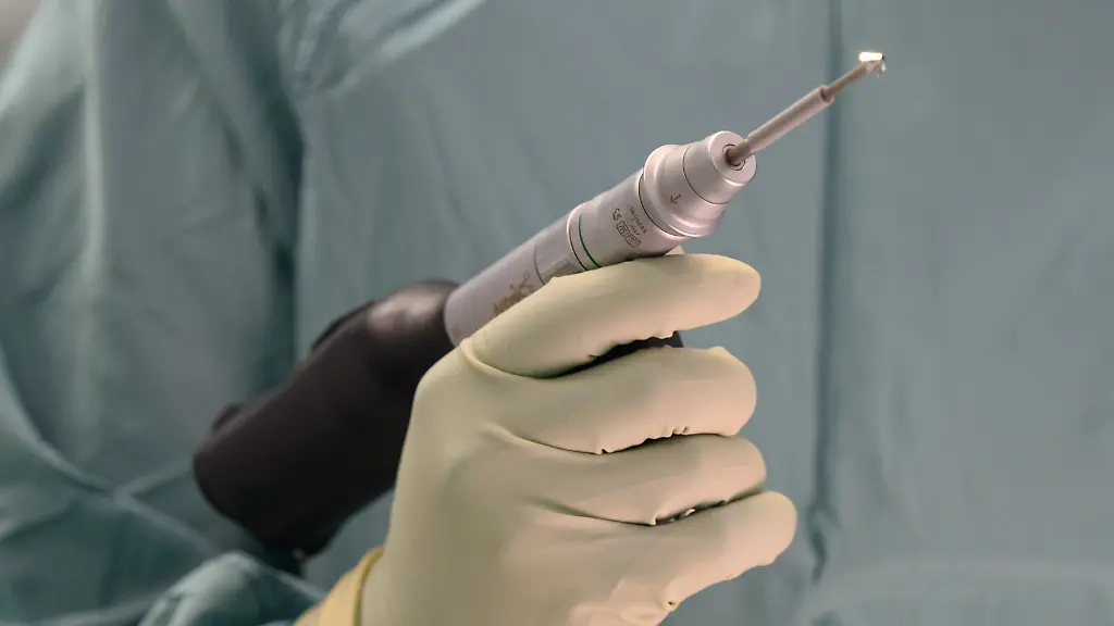 Ein-Arzt-haelt-in-einem-Operationssaal-eine-Bohrmaschine-in-der-Hand-Symbolbild