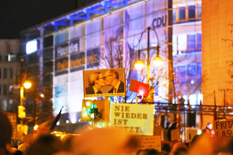 Berlin-Deutschland-Konrad-Adenauer-Haus-Demo-unter-dem-Motto-Aufstand-der-Anstaendigen-Wir-sind-die-Brandmauer-Schild-mit-einem-montierten-Kuss-zwischen-Friedrich-Merz-und-Alice-Weidel-Auf-der-unter-anderem-von-Camapct-organisierten-Grossdemo-wird-dagegen-protestiert-dass-CDU-und-CSU-zusammen-mit-der-AfD-im-Bundestag-Mehrheiten-erzielen