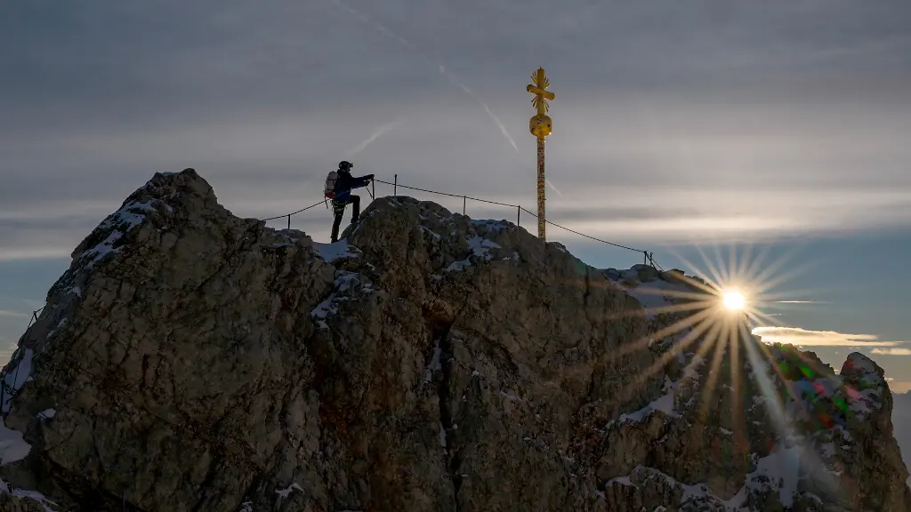 Das-Zugspitz-Gipfelkreuz-strahlt-in-den-fruehen-Morgenstunden-in-der-aufgehenden-Sonne-ueber-den-Bergen-Am-Mittag-soll-das-Kreuz-mit-einem-Helikopter-ins-Tal-geflogen-und-dort-von-einem-Kunstschmiede-Betrieb-restauriert-werden-Zum-Winter-Saisonstart-auf-der-Zugspitze-am-28-November-soll-das-Kreuz-wieder-an-seinem-Platz-auf-dem-Gipfel-sein