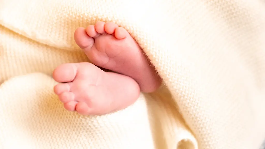 Nackte-Babyfuesse-ragen-aus-einer-warmen-Wolldecke-Aachen-Nordrhein-Westfalen-Deutschland-15-12-2021