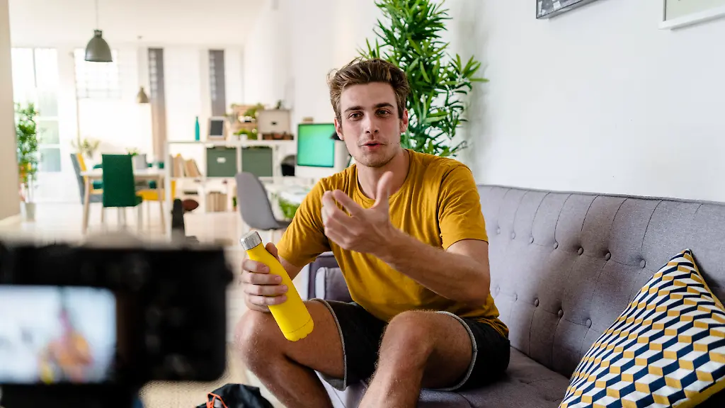 Fitness-trainer-live-streaming-fitness-session-while-sitting-on-sofa-at-home-model-released-Symbolfoto-property-released-GIOF08953