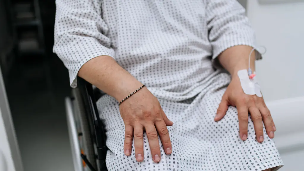 Close-up-of-man-in-wheelchair-with-IV-cannula-in-hand-Overweight-patient-in-hospital-gown-waiting-for-medical-examination-in-hospital-Close-up-of-man-in-wheelchair-with-IV-cannula-in-hand-Overweight-patient-in-hospital-gown-waiting-for-medical-examination-in-the-hospital