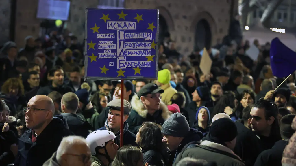 10-12-2025-Bulgarien-Sofia-Ein-Demonstrant-haelt-ein-Transparent-waehrend-eine-anschwellende-Menge-von-Zehntausenden-von-Bulgaren-den-zentralen-Platz-in-Sofia-fuellt-und-den-Ruecktritt-der-Regierung-inmitten-wachsender-Wut-ueber-Korruption-und-umstrittene-Wirtschaftspolitik-fordert