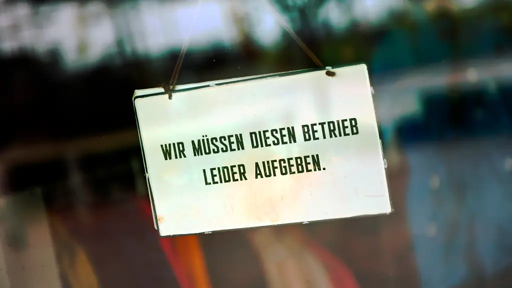 Schild-an-der-Glastuer-eines-Geschaefts-mit-der-Aufschrift-Wir-muessen-diesen-Betrieb-leider-aufgeben-Fotomontage