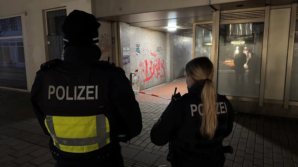 Polizisten-stehen-an-einem-Flatterband-Ein-16-Jaehriger-ist-im-ostwestfaelischen-Herford-bei-einem-Messerangriff-lebensgefaehrlich-verletzt-worden-Der-Vorfall-habe-sich-in-einer-Seitenstrasse-am-Rande-des-Weihnachtsmarkts-ereignet-teilte-ein-Sprecher-der-Polizei-mit