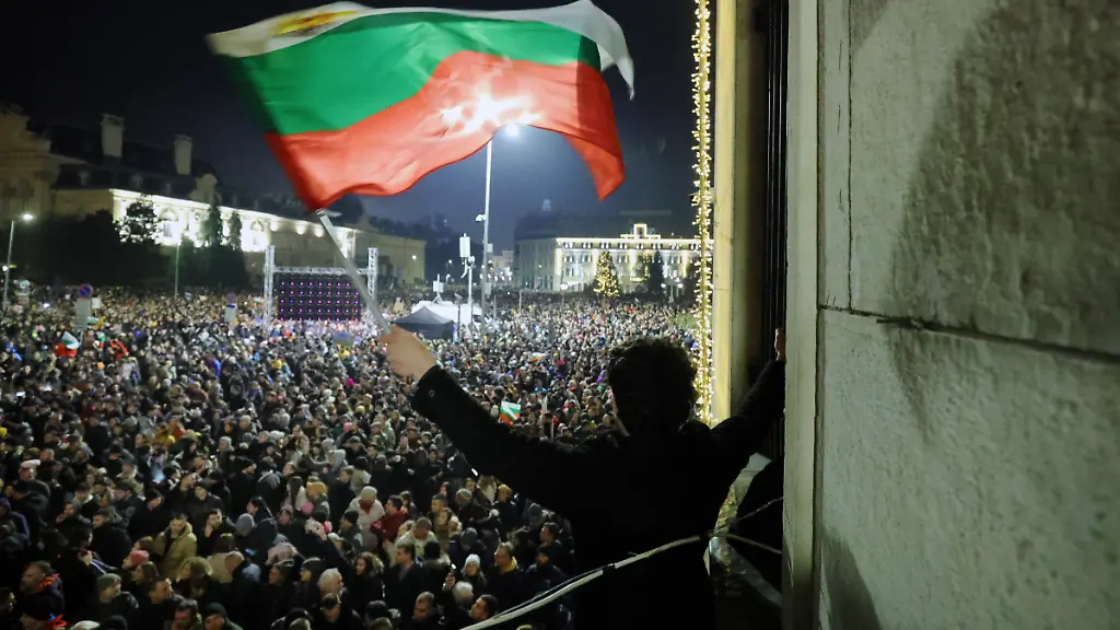 Ein-Student-schwenkt-eine-bulgarische-Flagge-waehrend-eine-anschwellende-Menge-von-Zehntausenden-von-Bulgaren-den-zentralen-Platz-in-Sofia-fuellt-und-den-Ruecktritt-der-Regierung-inmitten-wachsender-Wut-ueber-Korruption-und-umstrittene-Wirtschaftspolitik-fordert