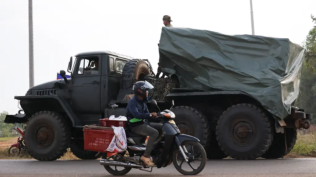 A-man-drives-past-a-military-vehicle-heading-towards-the-border-amid-deadly-clashes-between-Thailand-and-Cambodia-along-a-disputed-border-area-in-Srei-Snam-Siem-Reap-Province-Cambodia-December-10-2025