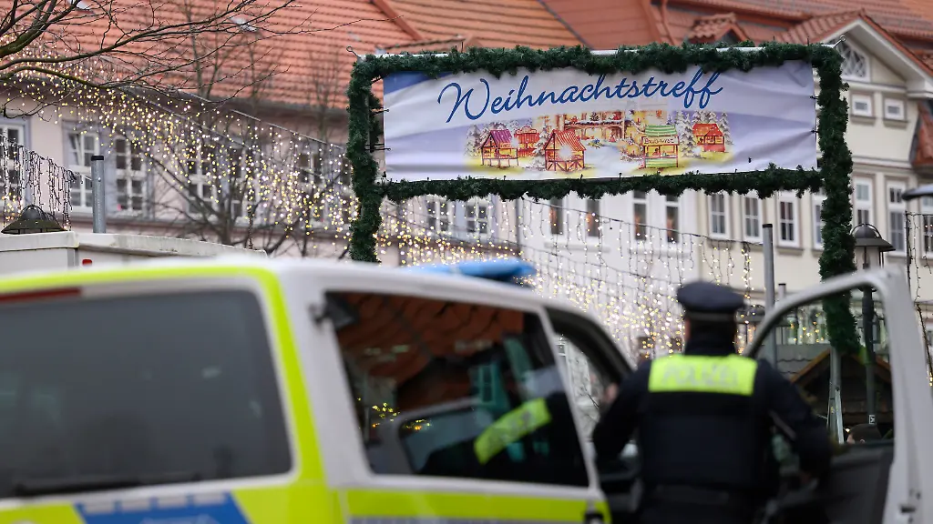 Einsatzkraefte-der-Polizei-stehen-am-Weihnachtstreff-Nach-der-Raeumung-des-Weihnachtsmarkts-am-12-12-2025-im-suedniedersaechsischen-Duderstadt-sucht-die-Polizei-weiter-nach-einem-Verdaechtigen-Mehrere-Zeugen-hatten-angegeben-am-Freitagabend-einen-Mann-mit-einer-Langwaffe-gesehen-zu-haben