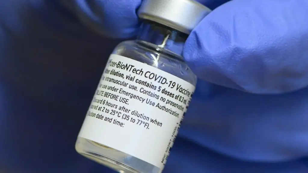 Eine-Mitarbeiterin-haelt-ein-Injektionsflaeschchen-mit-dem-Impfstoff-von-Biontech-Pfizer-gegen-Corona-in-den-Haenden