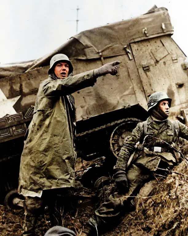 World-War-II-Battle-of-the-Bulge-Ardennes-Offensive-last-major-German-offensive-campaign-on-the-Western-Front-December-1944-January-1945-German-soldier-beside-a-disabled-American-half-track-signaling-his-unit-to-advance-during-the-counter-attack-the-Germans-launched-in-the-Belgian-sector-of-the-Western-Front-December-16-1944-Photo-from-a-captured-German-film-Photo-December-1944