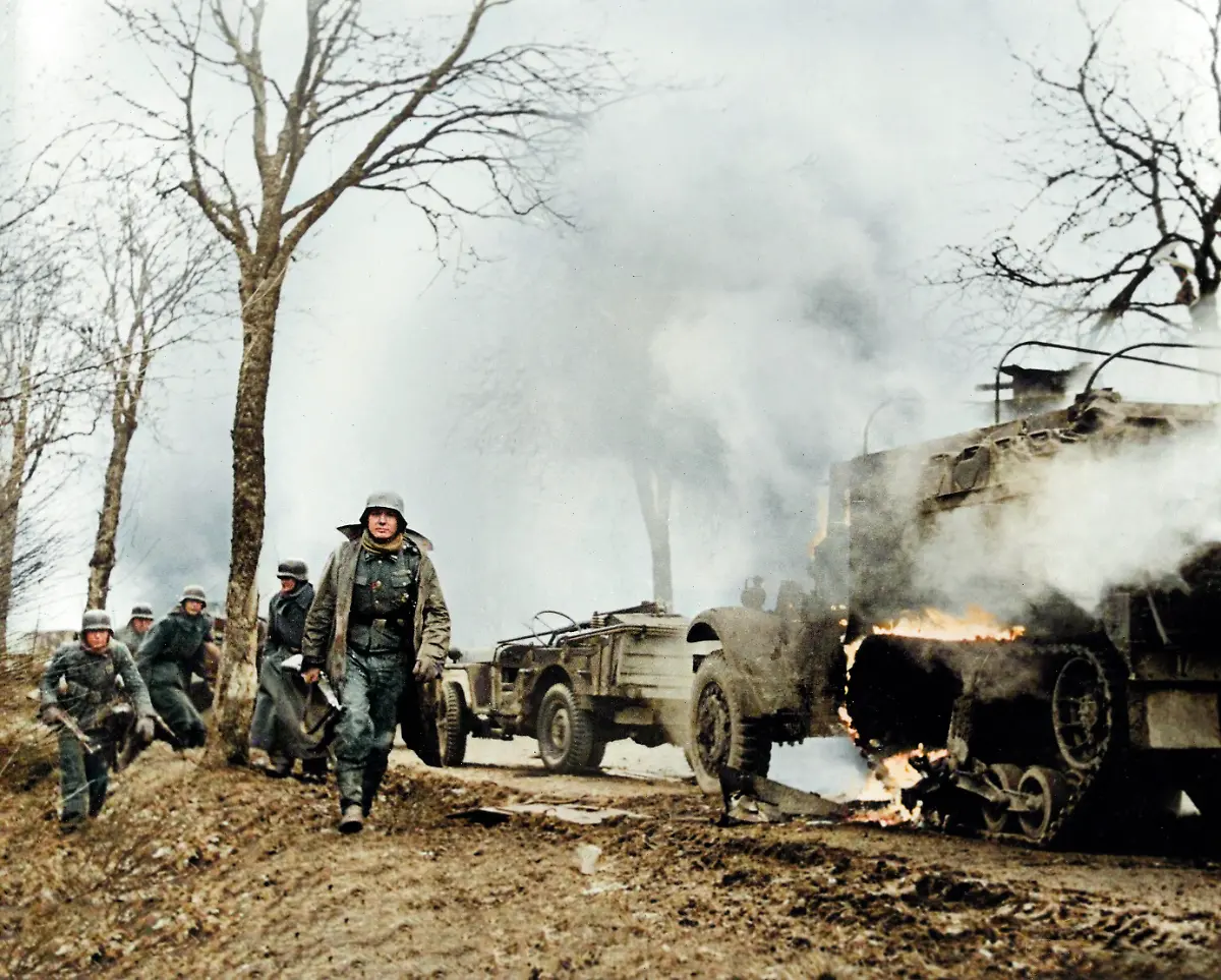 World-War-II-Battle-of-the-Bulge-Ardennes-Offensive-last-major-German-offensive-campaign-on-the-Western-Front-December-1944-January-1945-German-infantrymen-pass-burning-captured-American-vehicles-somewhere-on-front-during-German-drive-into-lines-photographed-by-a-German-army-camerman-whose-films-were-later-captured-by-American-forces-Photo-December-17-1945