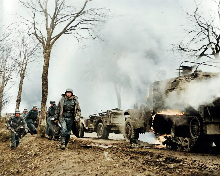 World-War-II-Battle-of-the-Bulge-Ardennes-Offensive-last-major-German-offensive-campaign-on-the-Western-Front-December-1944-January-1945-German-infantrymen-pass-burning-captured-American-vehicles-somewhere-on-front-during-German-drive-into-lines-photographed-by-a-German-army-camerman-whose-films-were-later-captured-by-American-forces-Photo-December-17-1945