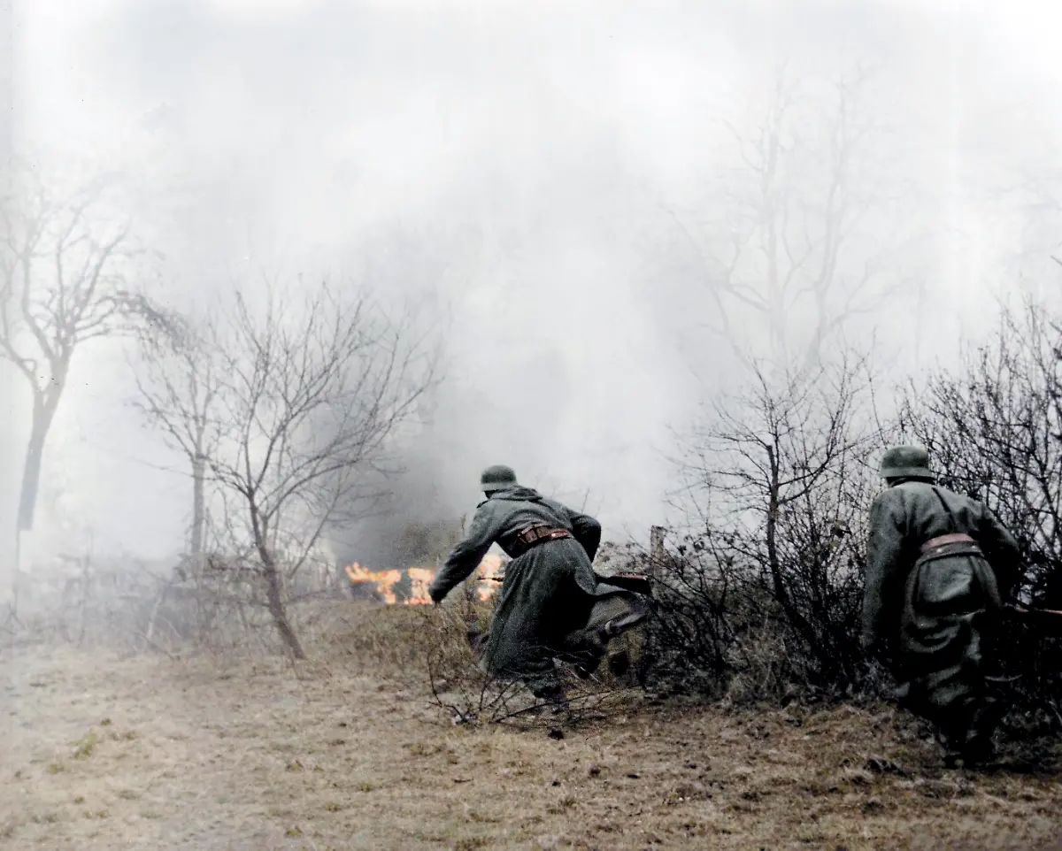 World-War-II-Battle-of-the-Bulge-Ardennes-Offensive-last-major-German-offensive-campaign-on-the-Western-Front-December-1944-January-1945-German-infantrymen-on-patrol-run-as-they-approach-burning-vehicle-photographed-by-a-German-army-camerman-whose-films-were-later-captured-by-American-forces-Photo-December-17-1945