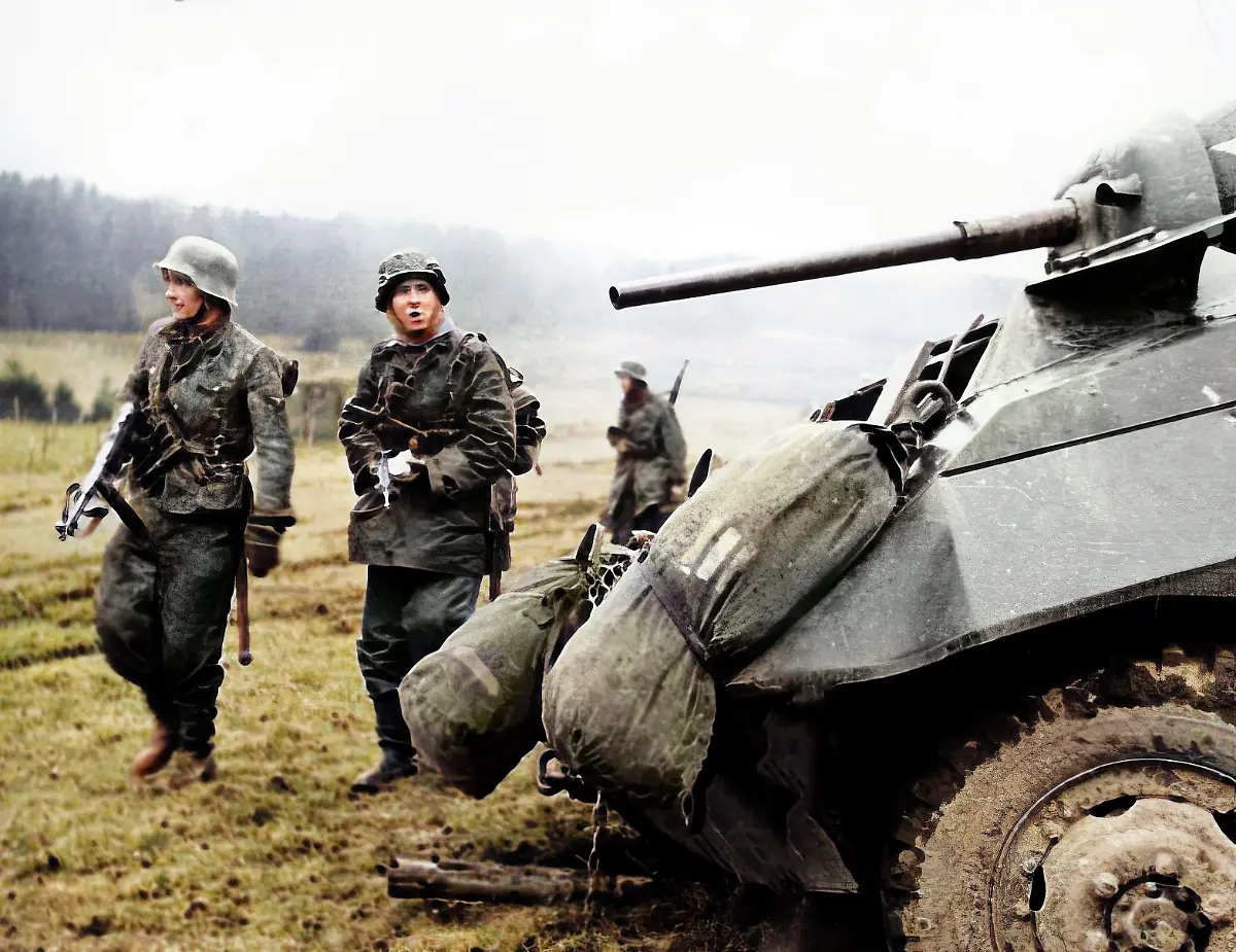 World-War-II-Battle-of-the-Bulge-Ardennes-Offensive-last-major-German-offensive-campaign-on-the-Western-Front-December-1944-January-1945-Two-German-soldiers-walk-by-a-tank-somewhere-between-Malmedy-and-St-Vith-Belgium-Photo-ca-1944