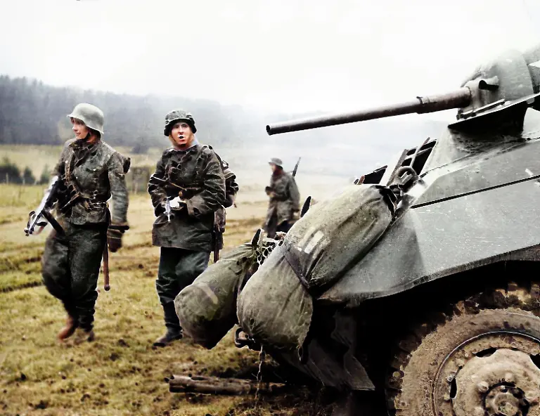 World-War-II-Battle-of-the-Bulge-Ardennes-Offensive-last-major-German-offensive-campaign-on-the-Western-Front-December-1944-January-1945-Two-German-soldiers-walk-by-a-tank-somewhere-between-Malmedy-and-St-Vith-Belgium-Photo-ca-1944