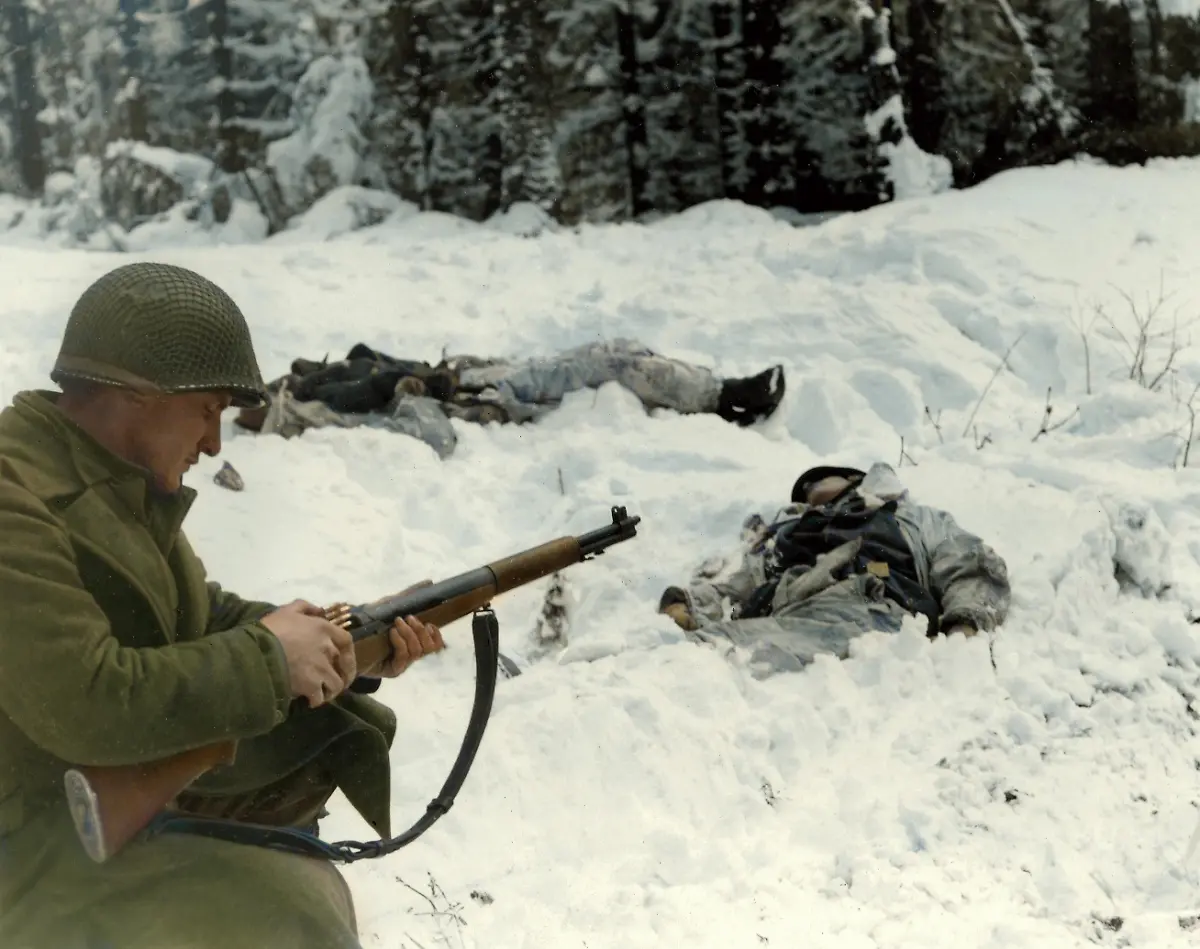 World-War-II-Battle-of-the-Bulge-Ardennes-Offensive-last-major-German-offensive-campaign-on-the-Western-Front-December-1944-January-1945-Pfc-Frank-Vukasin-Great-Falls-Mont-stops-to-load-clip-in-rifle-while-advancing-in-snow-covered-front-line-sector-at-Houffalize-Belgium-Two-dead-Germans-are-wearing-camouflaged-snow-uniforms-Company-C-331st-Infantry-Regiment-83rd-Infantry-Division-Photo-1944-45
