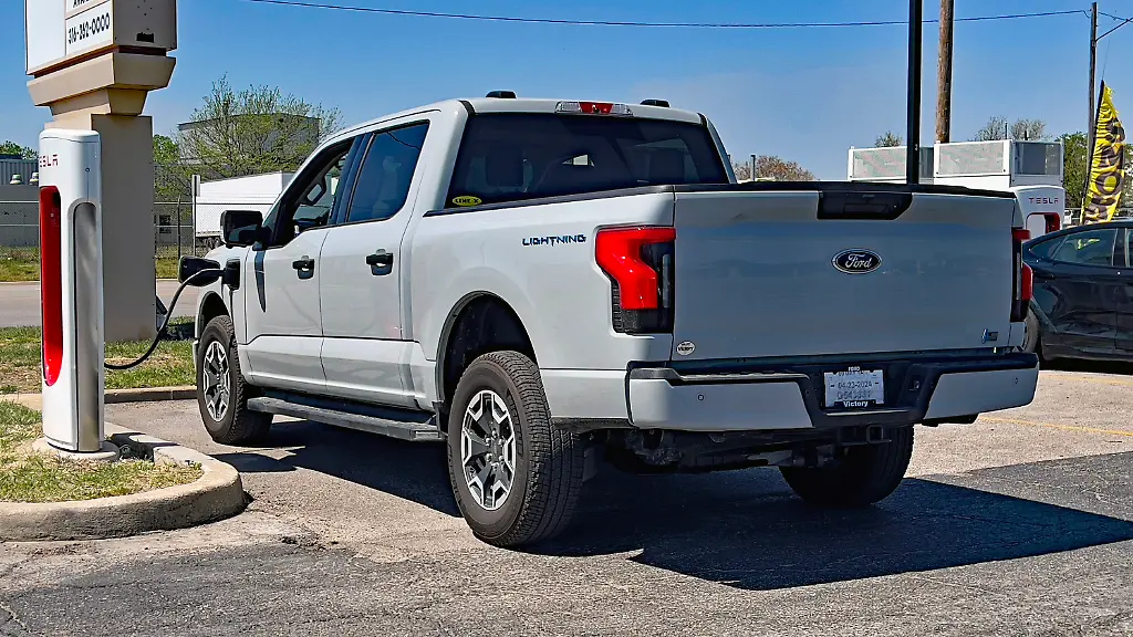 April-14-2024-Emporia-Kansas-U-S-A-recently-purchased-Ford-F150-all-electric-Lightning-pickup-truck-is-plugged-into-a-Tesla-Supercharger-station-in-the-parking-lot-of-the-Emporia-West-Shopping-plaza