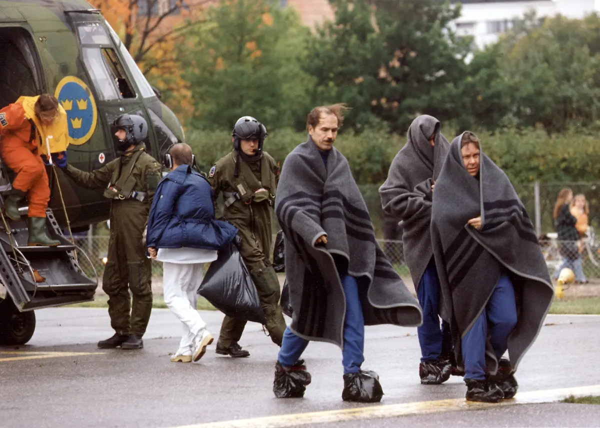 In-Decken-gehuellte-Ueberlebende-der-Estonia-Faehre-verlassen-am-28-9-1994-auf-der-Insel-Utoe-einen-Militaerhubschrauber-Die-Havariekommission-zum-Untergang-der-Estonia-hat-am-3-12-1997-einen-Baufehler-am-Bugvisier-als-entscheidende-Ursache-der-Katastrophe-bezeichnet-bei-der-am-28-September-1994-852-Reisende-starben-In-dem-mehr-als-drei-Jahre-nach-dem-Untergang-in-Tallinn-Stockholm-und-Helsinki-veroeffentlichten-Bericht-hiess-es-ueber-die-Konstruktion-des-1981-auf-der-Meyer-Werft-in-Papenburg-Emsland-vom-Stapel-gelaufenen-Schiffes-Die-Verriegelungen-des-Bugvisiers-haetten-um-ein-Mehrfaches-staerker-sein-muessen