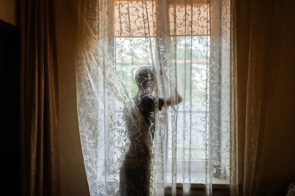 Toretsk-2021-A-young-boy-closes-a-window-while-the-sounds-of-fighting-can-be-heard-in-the-distance