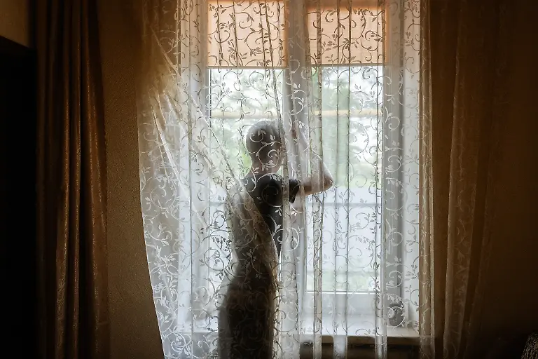 Toretsk-2021-A-young-boy-closes-a-window-while-the-sounds-of-fighting-can-be-heard-in-the-distance