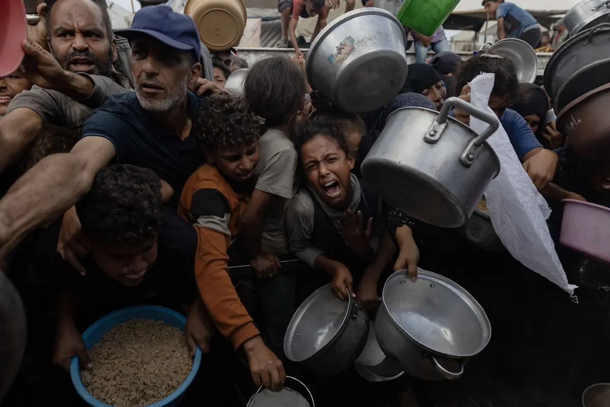 NYTCEASEFIRE-September-21-2025-Mawasi-Khan-Yunis-Children-women-and-men-wait-in-front-of-a-free-charity-kitchen-outside-their-displacement-camps-in-the-Mawasi-area-of-Khan-Yunis-to-receive-a-free-meal-due-to-their-deteriorating-economic-situation-and-their-inability-to-purchase-their-necessities-from-the-markets