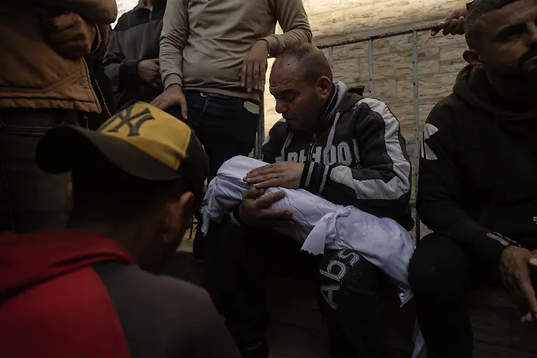 NYTCEASEFIRE-Palestinians-stand-around-the-bodies-of-their-relatives-who-were-killed-in-Israeli-air-strikes-at-the-Baptist-Hospital-in-Gaza-City-March-18-2025