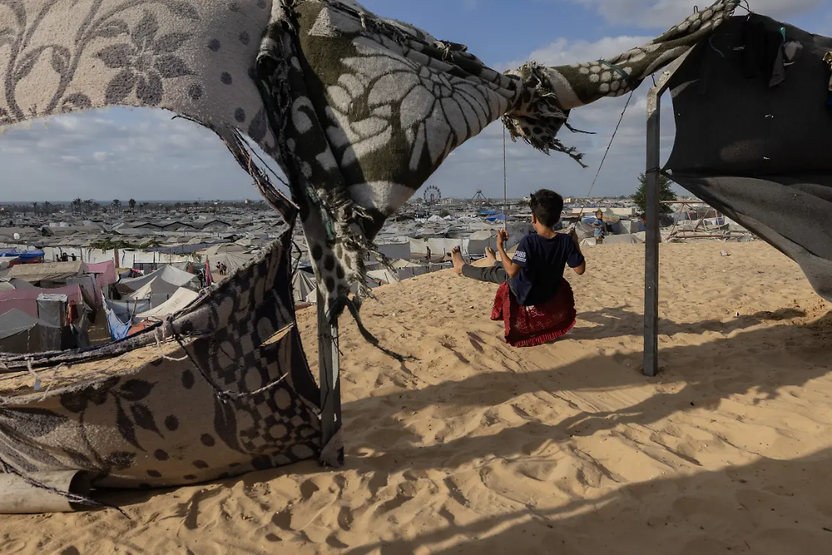 NYTCEASEFIRE-September-29-2025-Ziad-a-child-displaced-from-Khan-Younis-plays-on-a-swing-in-a-camp-housing-people-recently-displaced-from-eastern-Khan-Younis-and-Rafah-in-the-Mawasi-area-of-Khan-Yunis-south-of-the-Gaza-Strip