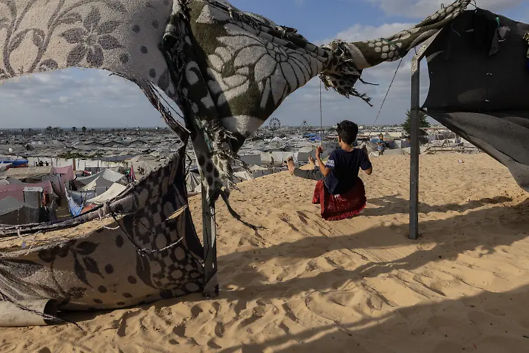 NYTCEASEFIRE-September-29-2025-Ziad-a-child-displaced-from-Khan-Younis-plays-on-a-swing-in-a-camp-housing-people-recently-displaced-from-eastern-Khan-Younis-and-Rafah-in-the-Mawasi-area-of-Khan-Yunis-south-of-the-Gaza-Strip