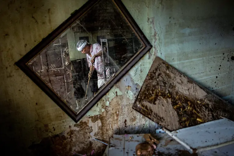 Eusebio-Cuyos-75-is-reflected-in-a-mirror-as-he-sweeps-mud-out-of-his-home-after-heavy-flooding-brought-on-by-Typhoon-Kalmaegi-in-Bacayan-Cebu-City-Philippines-November-5-2025-REUTERS-Eloisa-Lopez-TPX-IMAGES-OF-THE-DAY-SEARCH-REUTERS-BEST-2025-FOR-THIS-STORY-SEARCH-REUTERS-2025-YEAR-END-FOR-ALL-2025-YEAR-END-GALLERIES