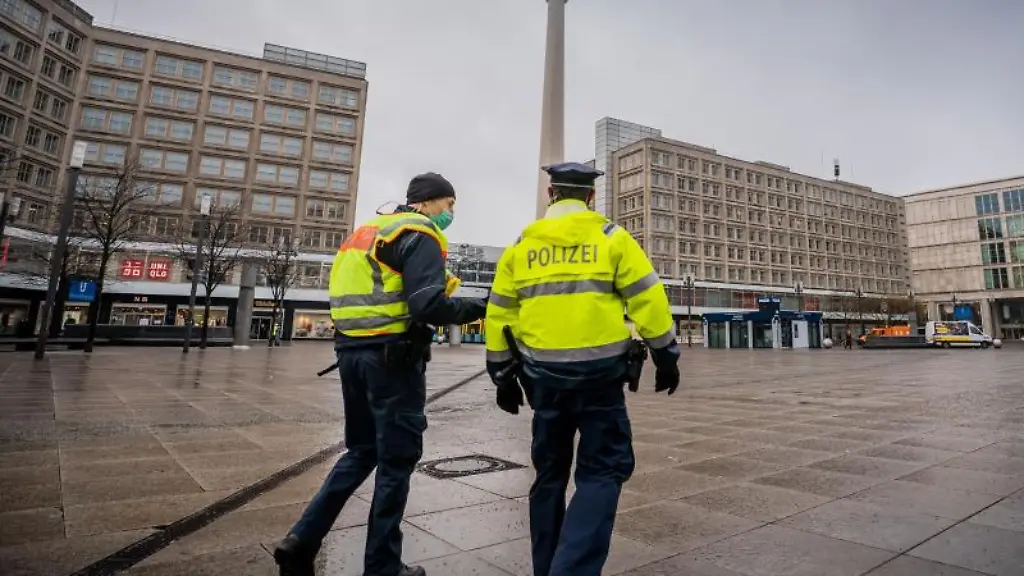 Polizisten-gehen-ueber-den-ansonsten-weitgehend-leeren-Alexanderplatz-in-der-Hauptstadt