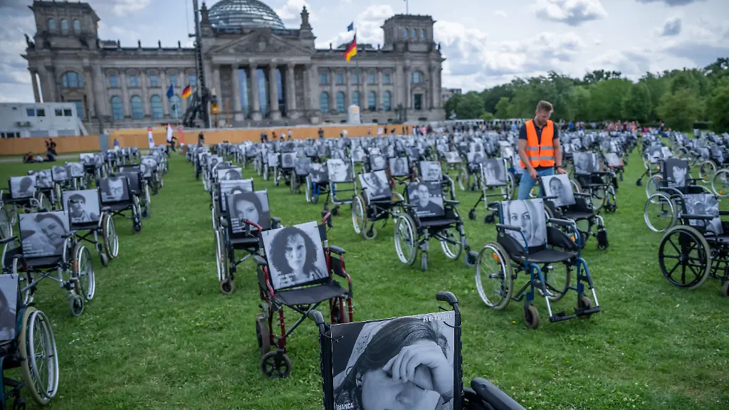 Rollstuehle-mit-Bildern-und-Namen-von-Long-Covid-ME-CFS-und-Post-Vac-Betroffenen-stehen-im-Jahr-2023-bei-einer-Demonstration-vor-dem-Reichstagsgebaeude-dem-Sitz-des-Deutschen-Bundestag-Mit-der-Aktion-wollte-die-Organisation-Nichtgenesen-auf-die-Schicksale-der-Betroffenen-Langzeiterkrankten-hinweisen