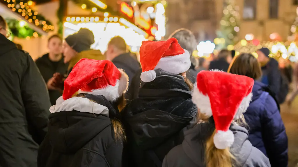 Besucher-mit-Weihnachtsmannmuetzen-laufen-ueber-den-Hildesheimer-Weihnachtsmarkt-auf-dem-historischen-Marktplatz