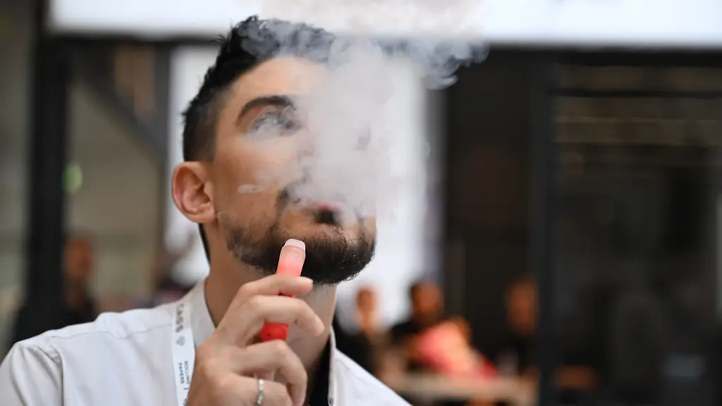 Ein-Besucher-der-Fachmesse-Intertabac-steht-an-einem-Messestand-eines-E-Zigaretten-Herstellers-und-dampft-Liquid-einer-E-Zigarette-Auf-der-weltgroessten-Tabakmesse-stellen-Hersteller-von-Zigaretten-E-Zigaretten-Tabakprodukten-und-Nikotinbeuteln-ihre-Waren-vor