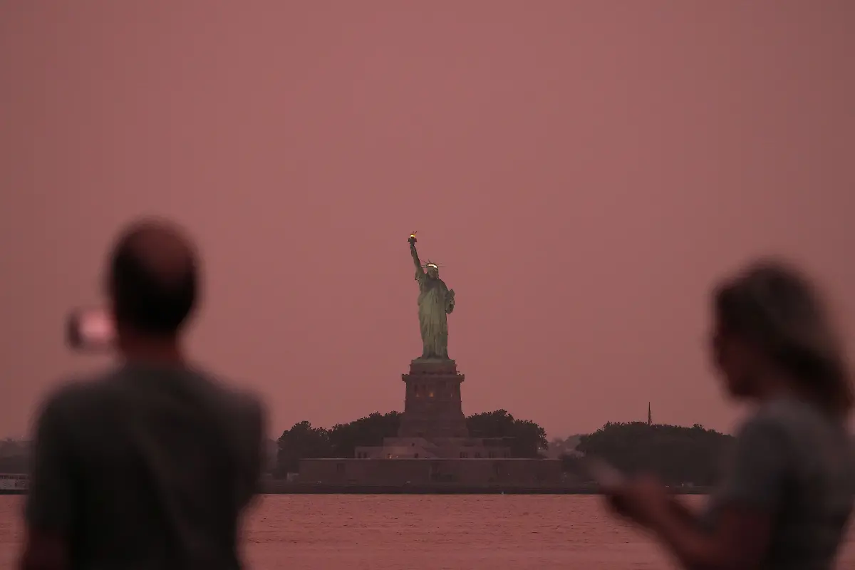 People-take-photographs-as-the-Statue-of-Liberty-is-seen-at-sunset-through-haze-caused-by-smoke-from-Canadian-wildfires-as-viewed-from-Brooklyn-New-York-August-6-Hundreds-of-wildfires-in-Canada-this-year-forced-the-evacuation-of-tens-of-thousands-of-residents-while-producing-haze-that-affected-one-third-of-the-United-States-that-was-also-visible-in-Europe