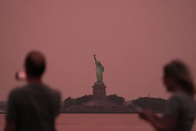 People-take-photographs-as-the-Statue-of-Liberty-is-seen-at-sunset-through-haze-caused-by-smoke-from-Canadian-wildfires-as-viewed-from-Brooklyn-New-York-August-6-Hundreds-of-wildfires-in-Canada-this-year-forced-the-evacuation-of-tens-of-thousands-of-residents-while-producing-haze-that-affected-one-third-of-the-United-States-that-was-also-visible-in-Europe