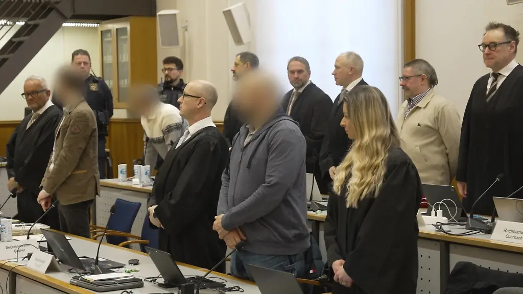 Die-Angeklagten-und-ihre-Anwaelte-stehen-auf-als-das-Gericht-den-Saal-betritt-Nach-fast-zwei-Jahren-koennte-heute-im-Prozess-ein-Urteil-fallen-Die-insgesamt-fuenf-Angeklagten-sollen-laut-Generalbundesanwalt-einen-gewaltsamen-Umsturz-in-Deutschland-die-Entfuehrung-von-Bundesgesundheitsminister-Lauterbach-SPD-und-einen-mehrwoechigen-Stromausfall-geplant-haben