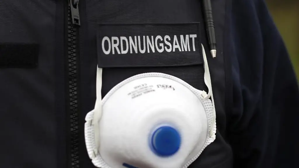 Ein-Mitarbeiter-des-Ordnungsamtes-traegt-einen-Mundschutz-an-seiner-Weste